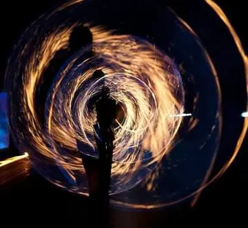 Prise de vue fascinante en longue exposition du feu tournant et de la silhouette la nuit.