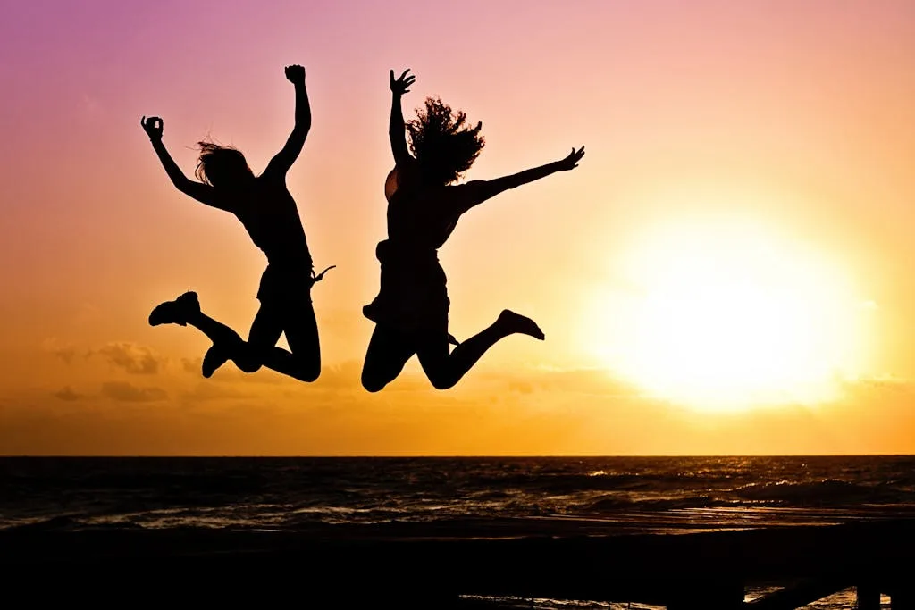 Deux personnes qui sautent devant un coucher de soleil